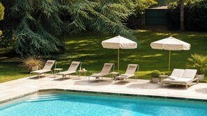 A swimming pool with lounge chairs and umbrellas, surrounded by a well-maintained lawn and trees. - Exclusive Estate - La Chapelle aux Acacias (Caucalières)