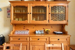 A wooden cabinet with glass doors, a countertop with kitchenware, and a sign indicating a coffee service. - Roma Family Terrace, Spacious Apt in San Giovanni (Rome)