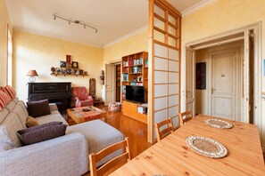 A living room with a sofa, a TV, a bookshelf, and a dining table. - Roma Family Terrace, Spacious Apt in San Giovanni (Rome)