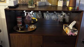 A wooden cabinet with multiple drawers, a tray with decorative items, and a variety of glassware and bottles.