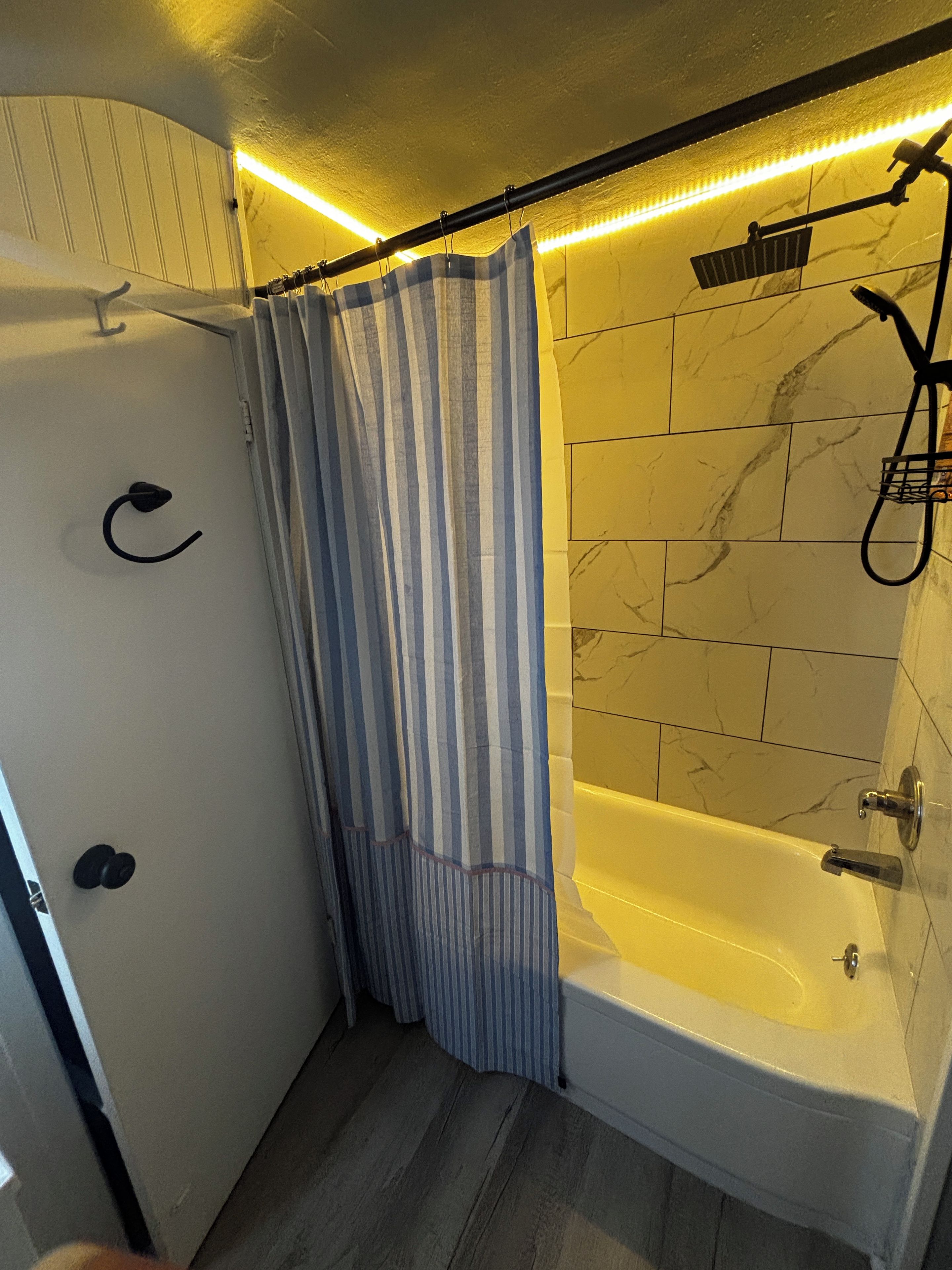Ein Badezimmer mit einer Badewanne, einer Dusche und einem gestreiften Vorhang.