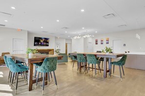 A modern dining area with wooden tables and teal upholstered chairs. - PremiumStays: Cozy, Modern, 1 bed loft - Downtown - Playhouse Square (Cleveland)