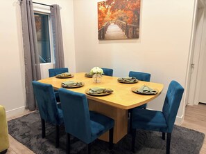 Ein Essbereich mit einem Holztisch, blau gepolsterten Stühlen und einem Bild einer Brücke an der Wand.