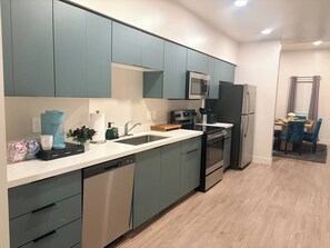 Una cocina moderna con armarios grises, lavavajillas, microondas y refrigerador.