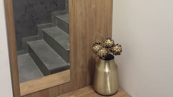 Un banco de madera con un jarrón de flores, un espejo y una puerta con manija.