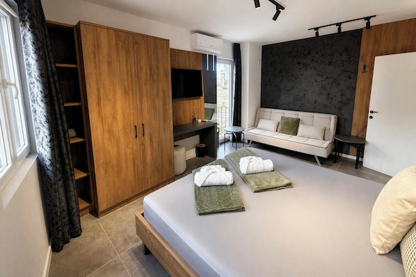 A modern bedroom with a bed, a sofa, a wardrobe, and a small table.