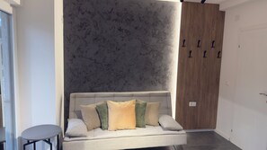 A modern interior with a grey sofa, a small round table, and a wooden door with black handles.