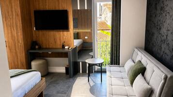 A modern hotel room with a bed, a desk, a sofa, and a TV.