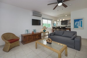 A living room with a grey sofa, wicker chair, and a glass coffee table. - Casa Christi - Private Pool, 2 BR, Sleeps 6 - Townhouse on the Right Side (Cozumel)