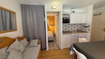 Ein kompakter Wohnraum mit Küchenzeile, Essbereich und Schlafzimmer.