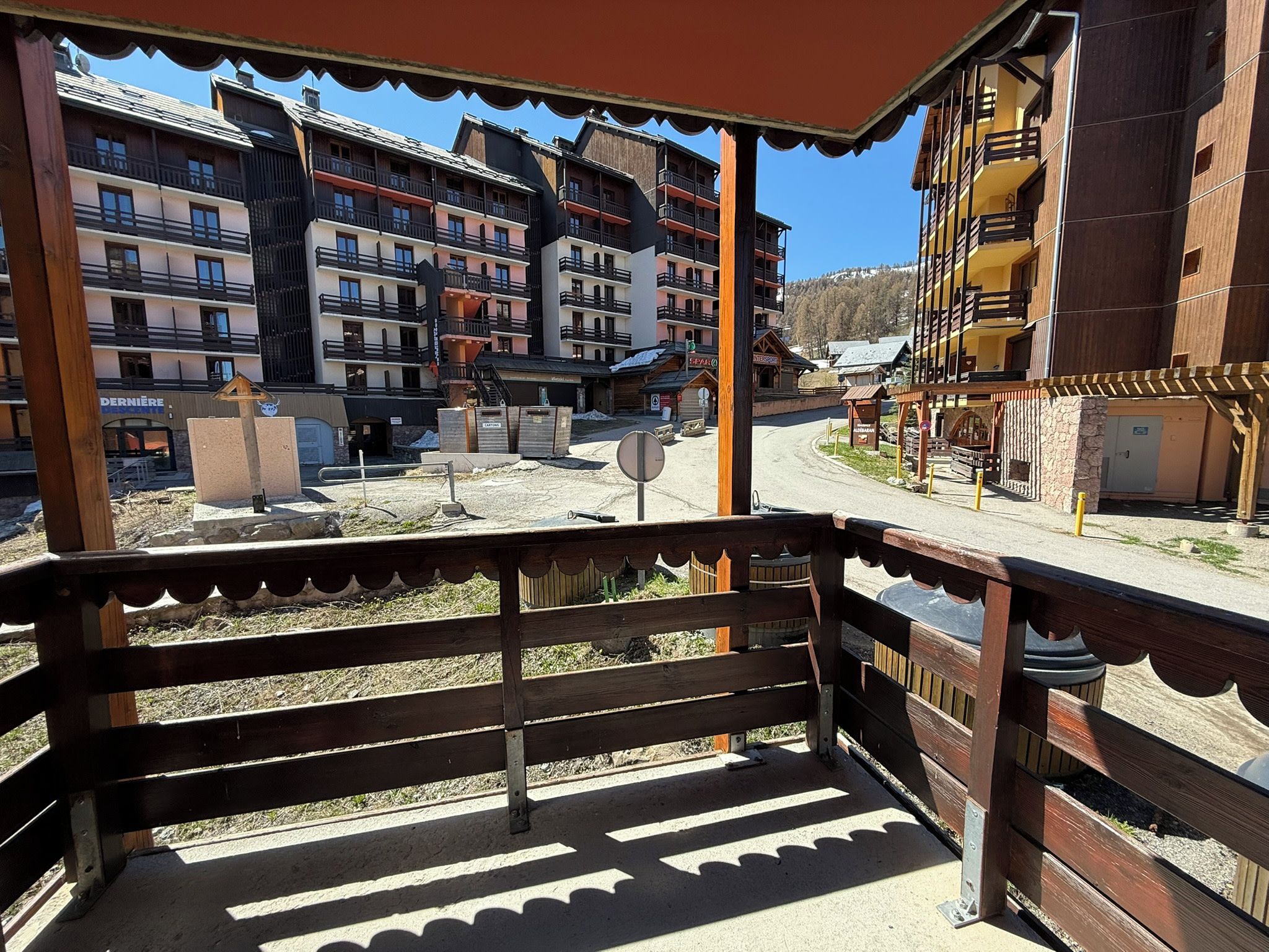 Un balcon offrant une vue sur un immeuble à plusieurs étages, doté lui-même de balcons, et sur un ciel dégagé.