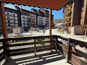 Un balcón con vistas a un edificio de varios pisos con balcones y cielo despejado.