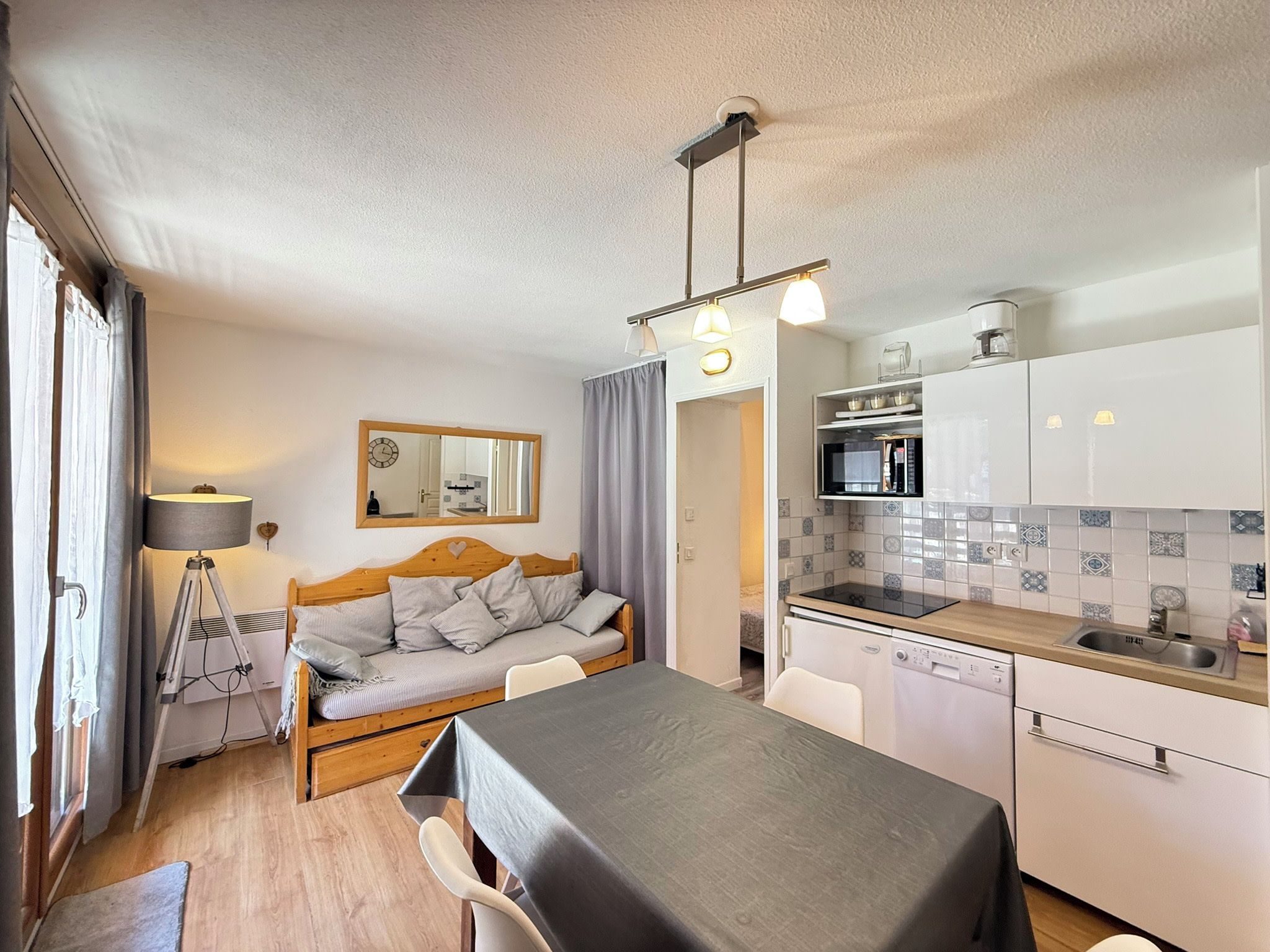 A compact room with a bed, a dining table, a kitchenette, and a small bathroom.