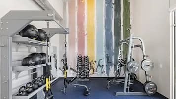 A gym with weightlifting equipment, kettlebells, and a wall with fitness illustrations.