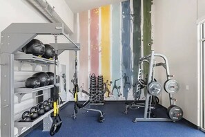 A gym with weightlifting equipment, kettlebells, and a wall with fitness illustrations. - Luxury 1BR Retreat | Pool, Gym & Gated Community (Mesa)