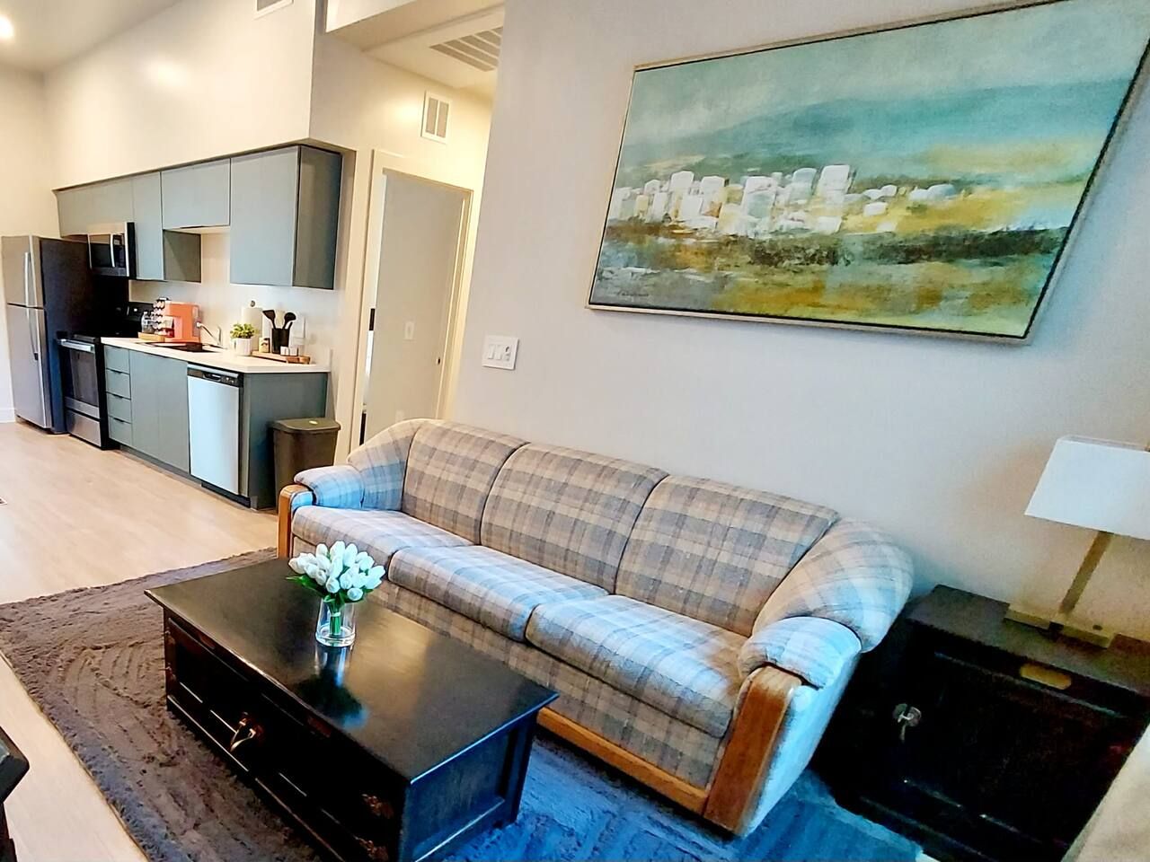 A living room with a sofa, coffee table, and a painting on the wall.