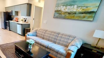 A living room with a sofa, coffee table, and a painting on the wall.