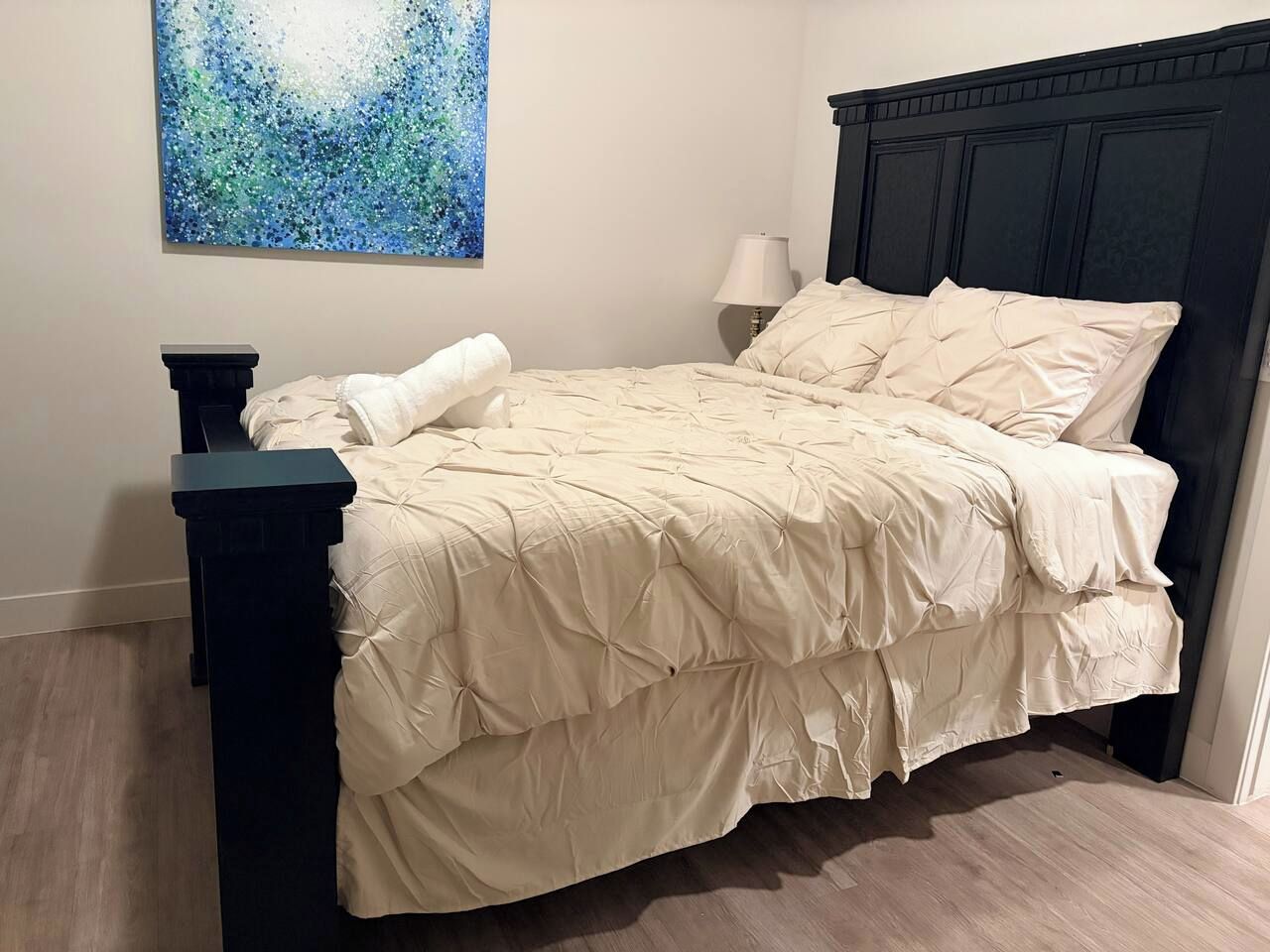 Une chambre à coucher avec un lit, une table de chevet, une lampe et un tableau au mur.