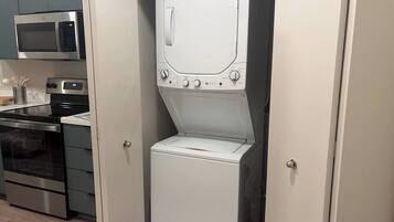 Een praktische keuken met een magnetron, oven en een ingebouwde was-droogcombinatie.