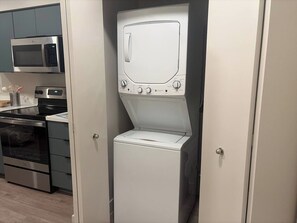 Een praktische keuken met een magnetron, oven en een ingebouwde was-droogcombinatie.