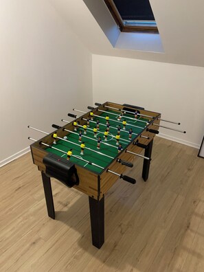 Una mesa de fútbolín en una habitación con suelo de madera y techo inclinado.