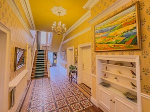 A hallway with patterned carpet, a staircase, a chandelier, and a painting on the wall. - Eden Mount, Wetheral -  a cottage that sleeps 10 guests  in 5 bedrooms (Wetheral)