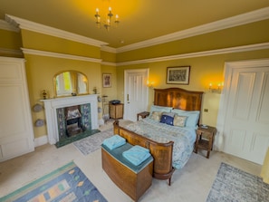 A spacious bedroom with a large bed, a fireplace, and a chandelier. - Eden Mount, Wetheral -  a cottage that sleeps 10 guests  in 5 bedrooms (Wetheral)