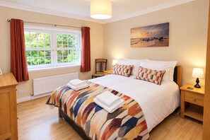 A hotel room with a large bed, a window with curtains, a painting on the wall, and a bedside table with a lamp. - Eden Grange, Wetheral, dog friendly cottage with stunning views (Wetheral)