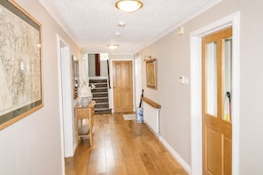A hallway with wooden flooring, a staircase, a door with a glass panel, and a framed map on the wall. - Eden Grange, Wetheral, dog friendly cottage with stunning views (Wetheral)