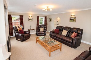 A living room with leather sofas, a glass coffee table, and a chandelier. - Eden Grange, Wetheral, dog friendly cottage with stunning views (Wetheral)