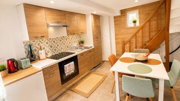 A modern kitchen with wooden cabinets, a built-in oven, and a dining area with a white table and chairs.