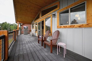 Eine Holzterrasse mit Stühlen, einem kleinen Tisch, einem Grill und Blick auf die Umgebung.