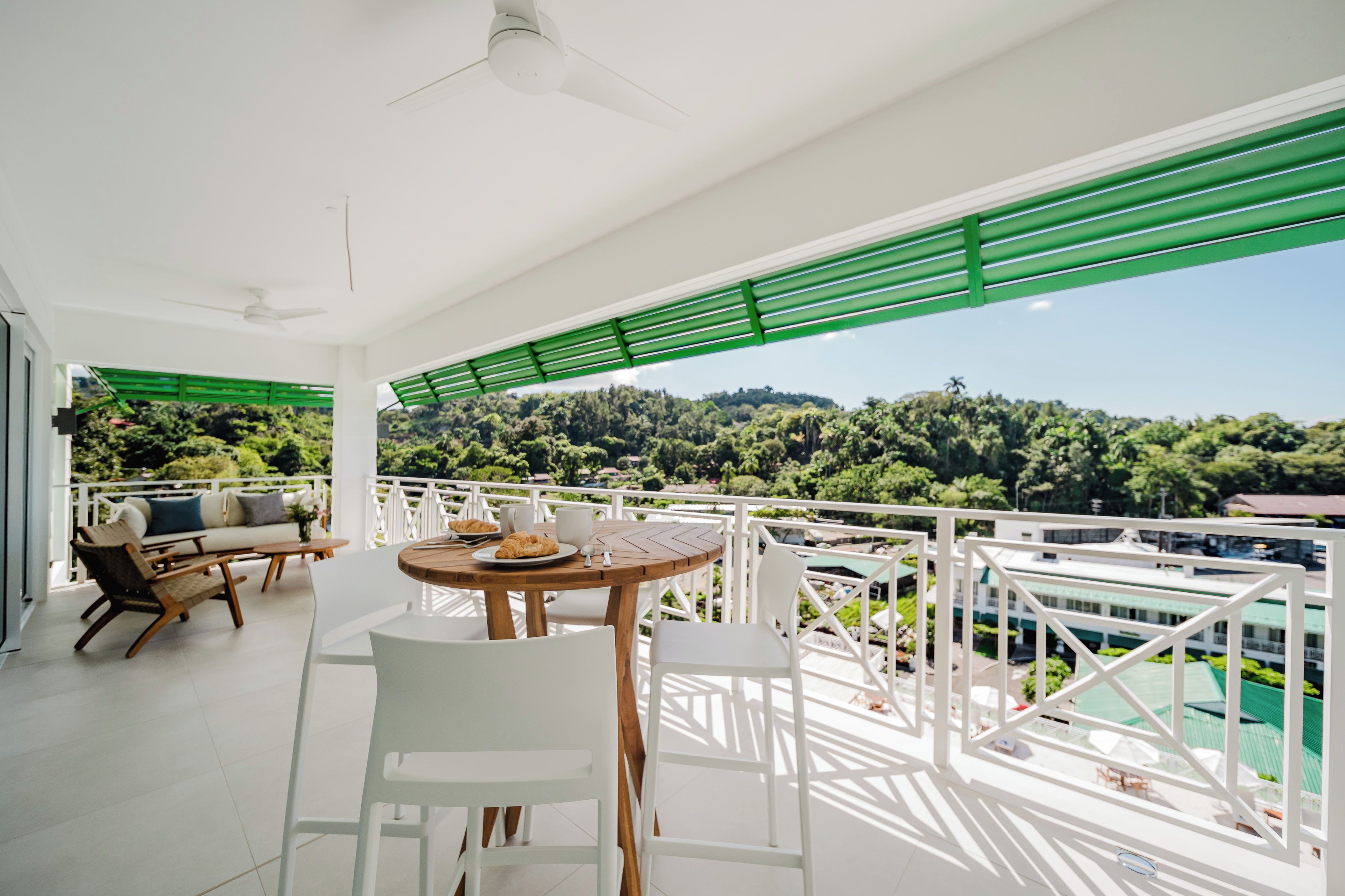 A balcony with a table, chairs, and a view of a lush green landscape.
