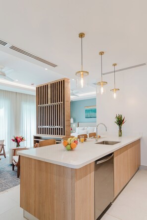 A modern kitchen with a central island, pendant lighting, and a built-in dishwasher. - Las Villas Marina Pez Vela  (Provincia de Puntarenas)
