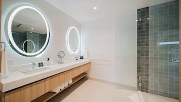 A modern bathroom with two large mirrors, a vanity with a sink, and a glass shower enclosure.