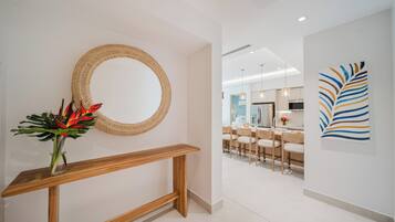 Un intérieur moderne agrémenté d’un grand miroir rond en fibres tressées, d’une console en bois et d’un coin repas avec des chaises et une table.