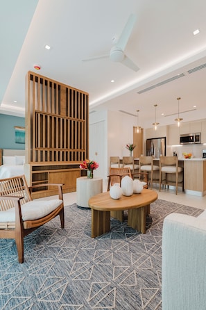 A modern living room with a wooden partition, a dining area with chairs, a round wooden table, and a kitchen with a microwave. - Las Villas Marina Pez Vela  (Provincia de Puntarenas)