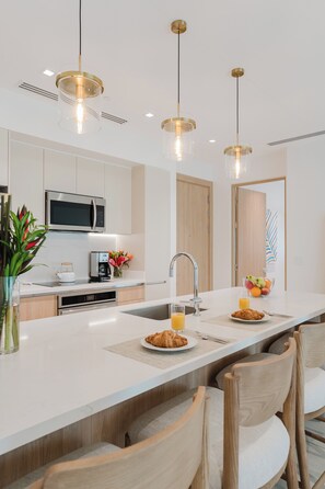 A modern kitchen with a central island, stainless steel appliances, and pendant lighting. - Las Villas Marina Pez Vela  (Provincia de Puntarenas)