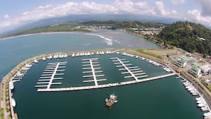 A marina with multiple docks and boats, surrounded by a coastal landscape with hills and a clear sky. - Las Villas Marina Pez Vela  (Provincia de Puntarenas)