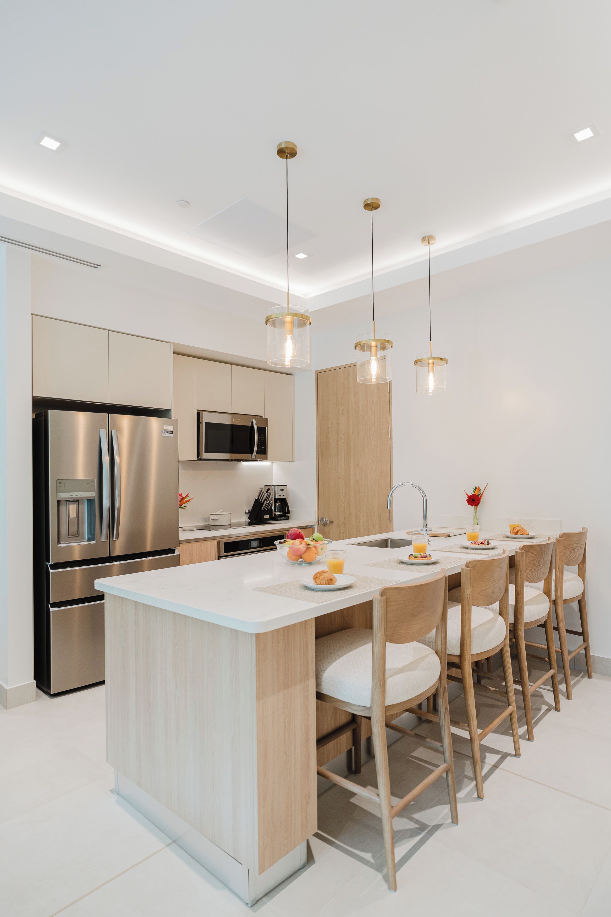 Una cucina moderna con isola centrale, elettrodomestici in acciaio inossidabile e illuminazione a sospensione.