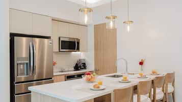 Una cucina moderna con isola centrale, elettrodomestici in acciaio inossidabile e illuminazione a sospensione.