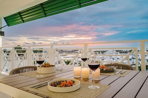 A table set for dinner with candles, wine glasses, and a bowl of food on a balcony overlooking a marina. - Las Villas Marina Pez Vela  (Provincia de Puntarenas)