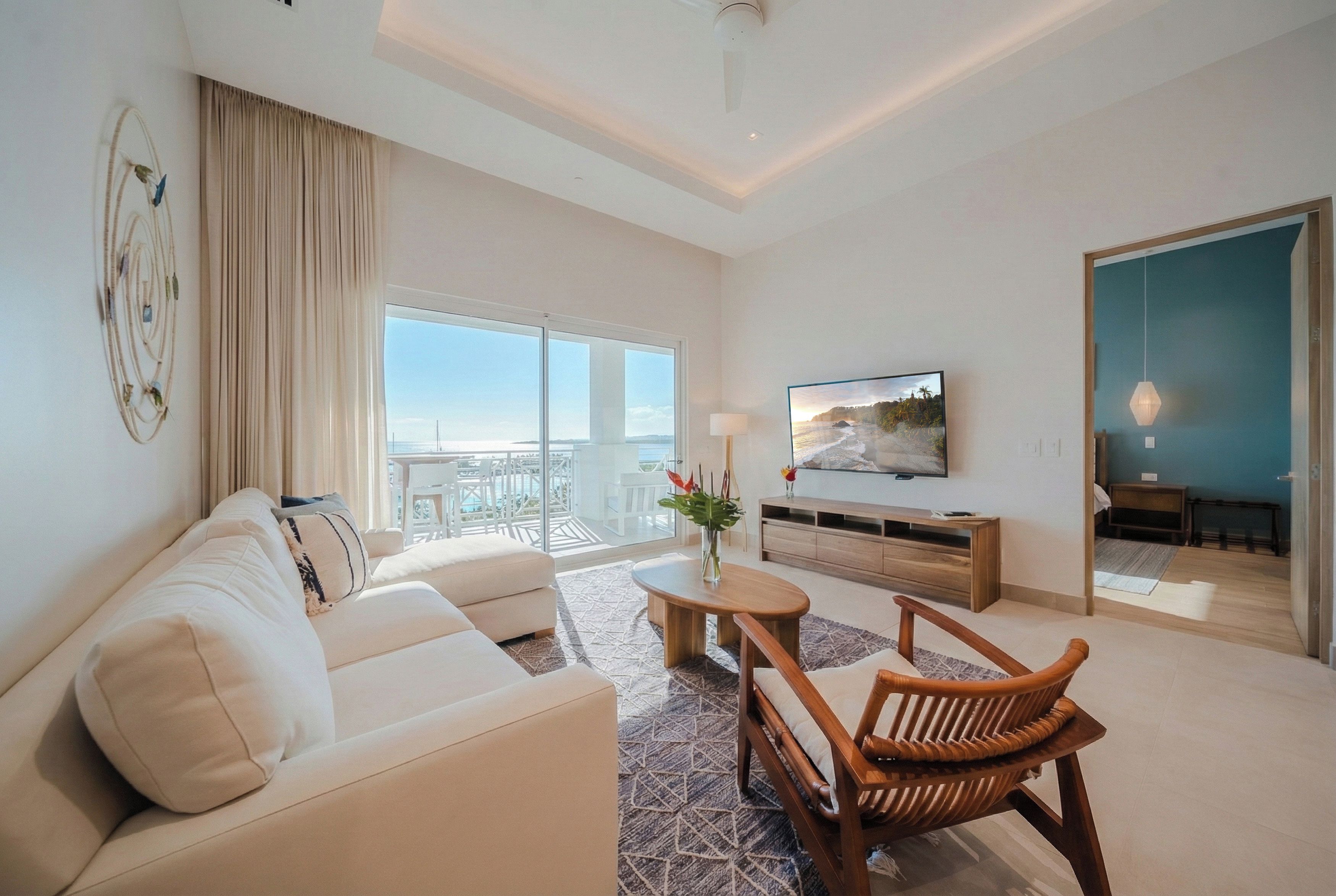 A modern living room with a sofa, a wooden chair, a coffee table, and a TV.