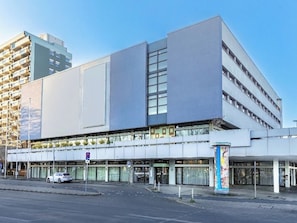 Een modern gebouw met een platte gevel, grote ramen en een overdekt entreegebied.