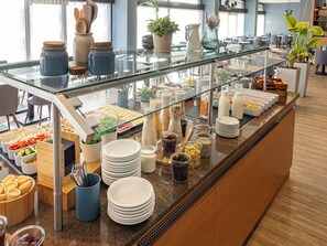 Een buffet met diverse soorten eten, bestek en bakjes.