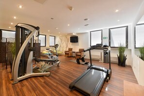 Een moderne sportschool met cardioapparaten, loopband en trainingsstoelen.