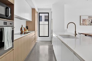 Eine moderne Küche mit Backofen, Mikrowelle, Spüle und Fenster.
