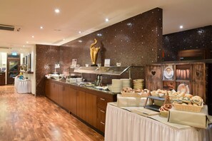 Een buffetgedeelte met diverse soorten eten, een groot gouden beeld en een betegelde muur.