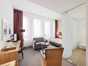 Een hotelkamer met een bureau, een bank, een bed, een kleine tafel en een badkamer.