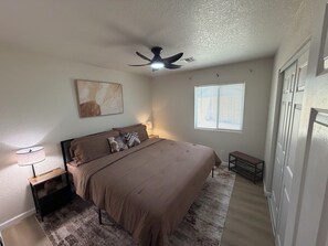 A bedroom with a bed, a ceiling fan, a window with blinds, a bedside lamp, and a wall-mounted artwork. - WINTER ESCAPE- PET-FRIENDLY 3BD+OFFICE NEAR GOLF COURSES, RIVER AND CASINOS (Mohave Valley)